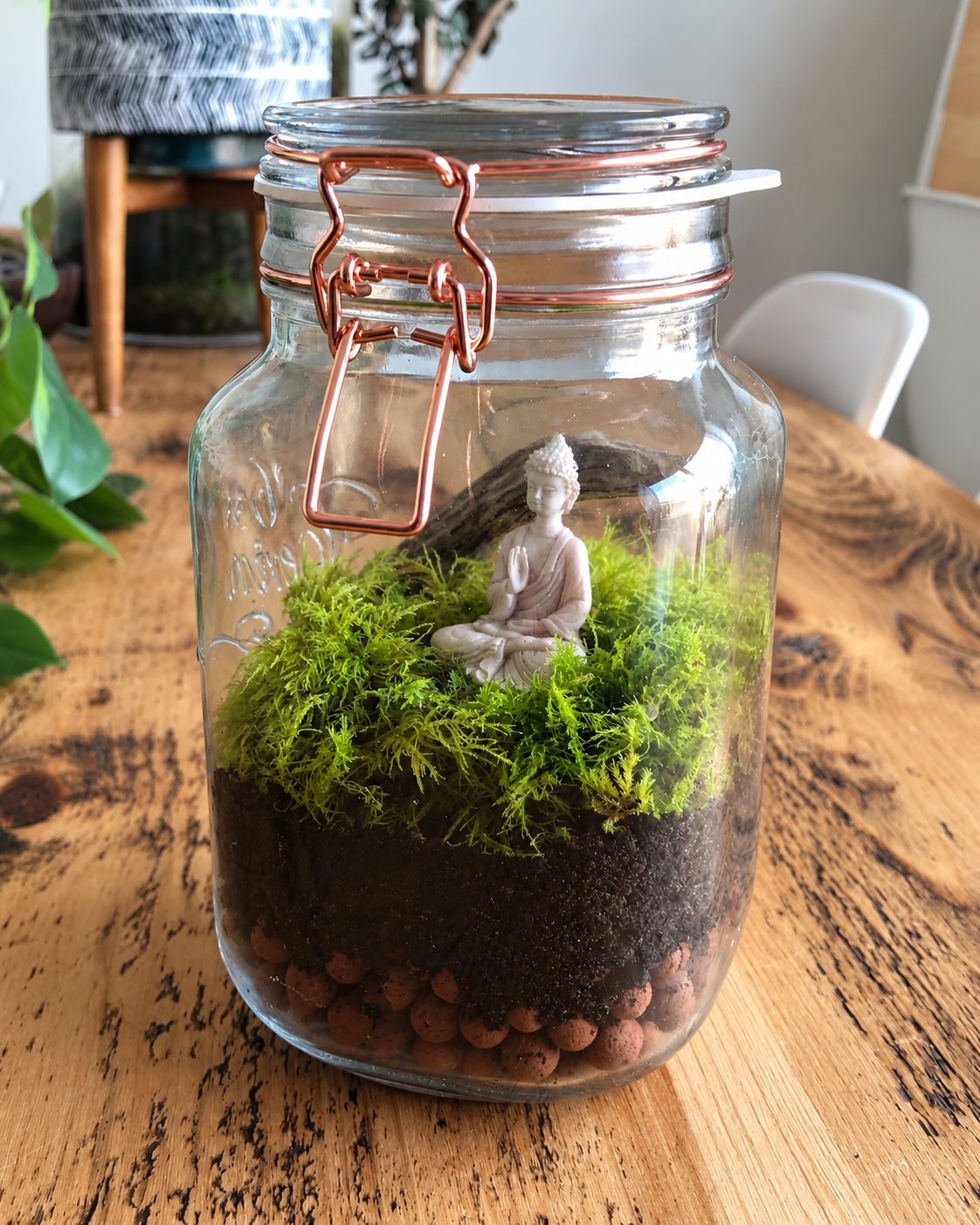 Tiny white Buddha figurine inside a live moss terrarium